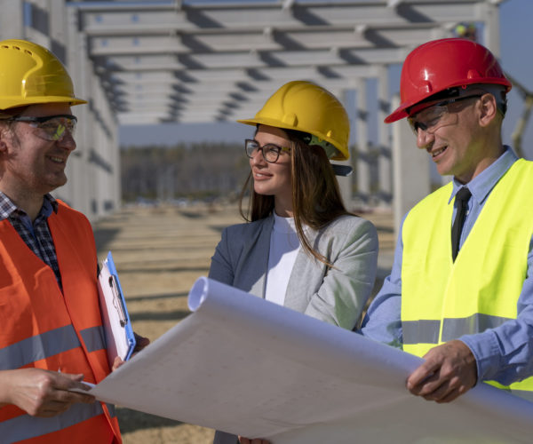 Group of Mixed Business People in Yellow and Red Hardhats Discuss a Project on Site Under Construction. Business, Building, Teamwork and People Concept.